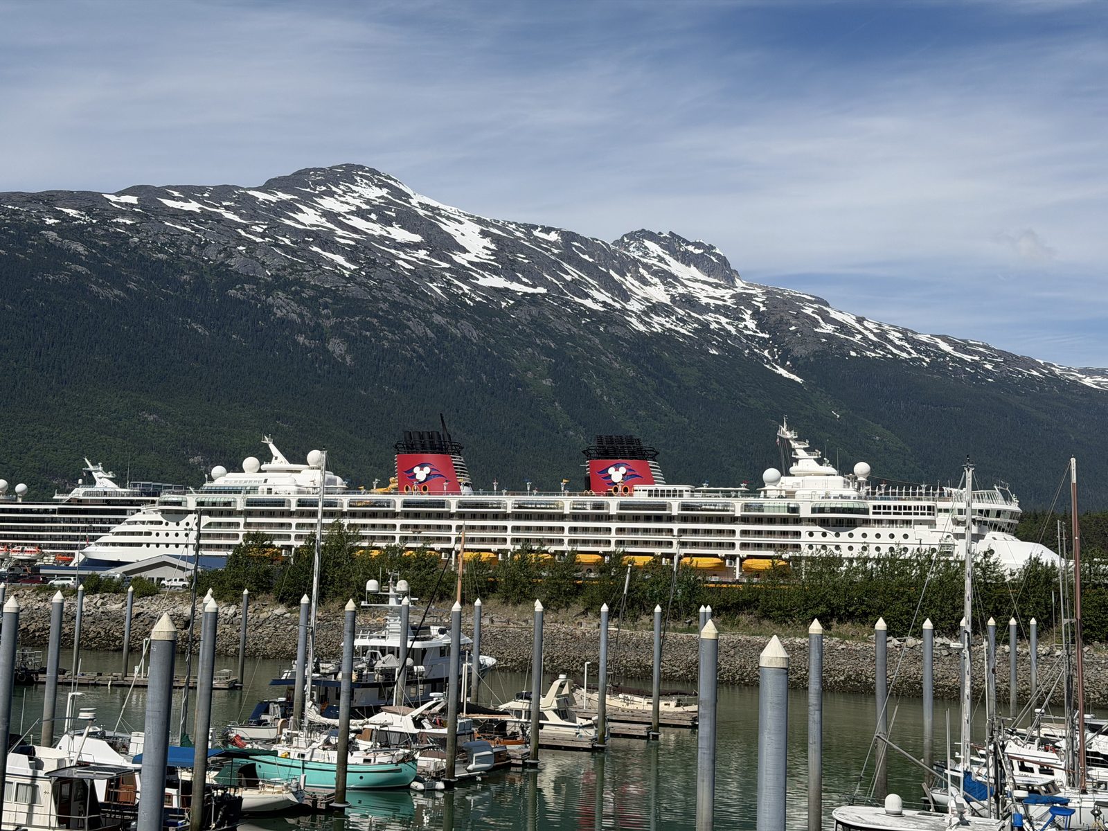 The Disney Magic in Skagway harbour under snow-streaked mountains