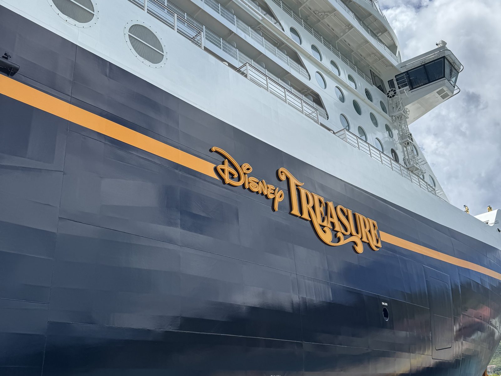 The Disney Treasure's dark hull and gold name, close up at the pier