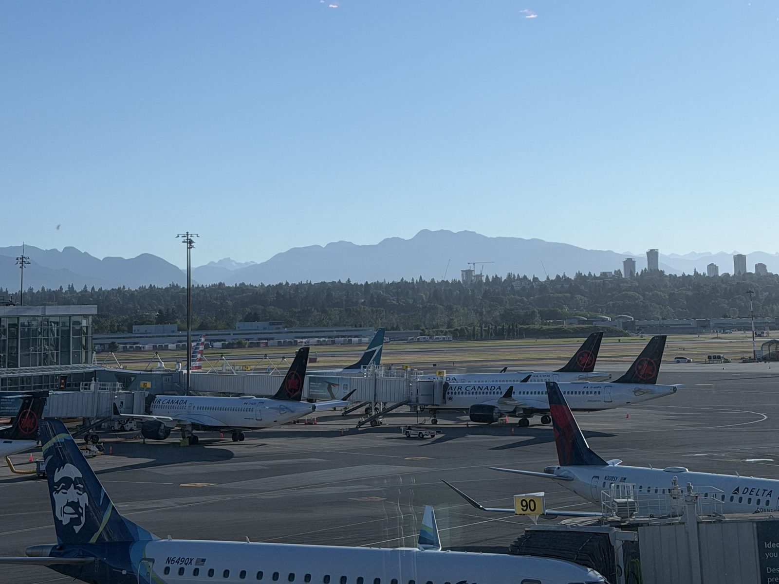 Planes at the gates at Vancouver airport, the mountains behind