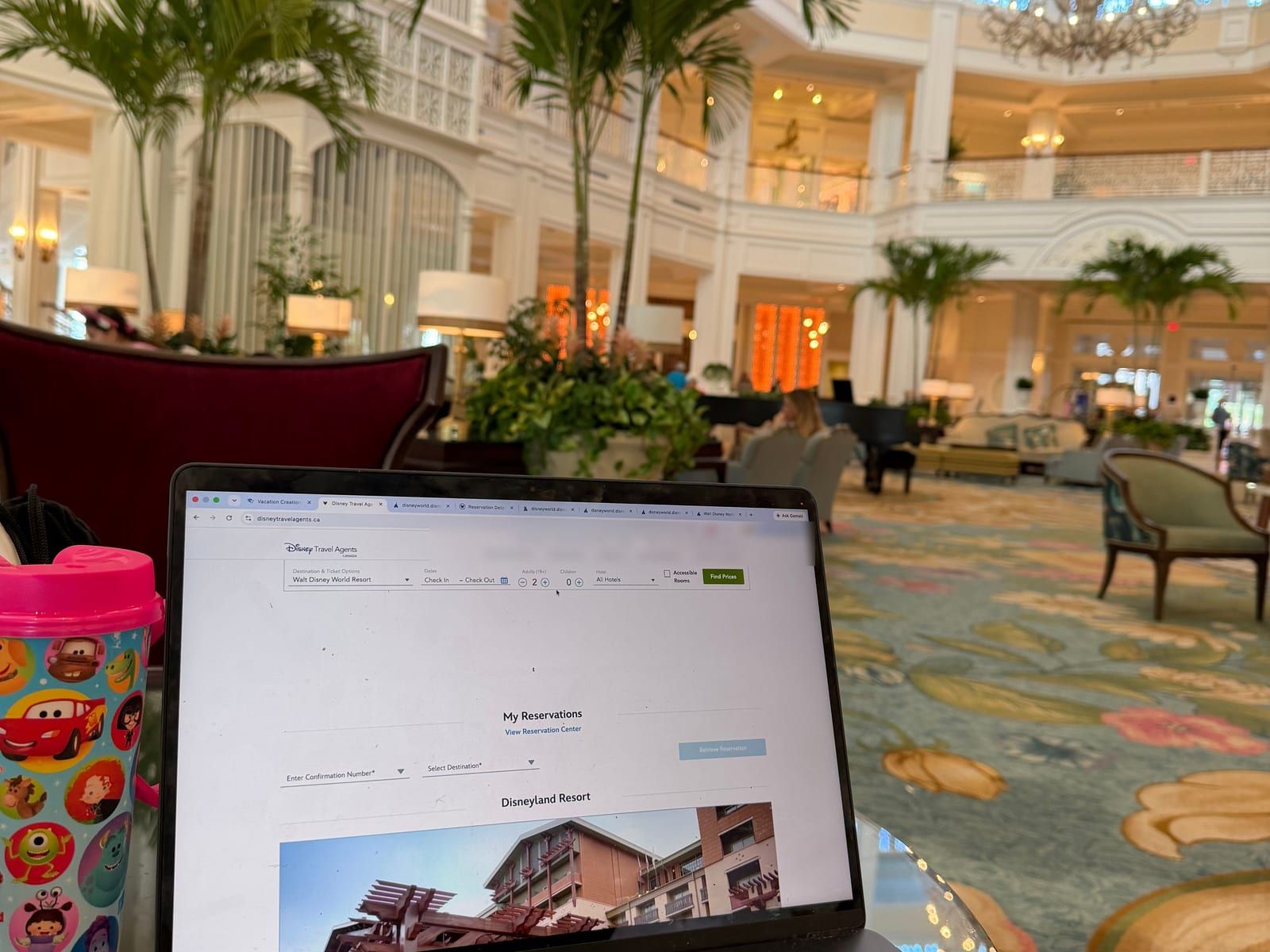Michelle's laptop open on the agent portal in a resort lobby, a coffee at hand and palms overhead