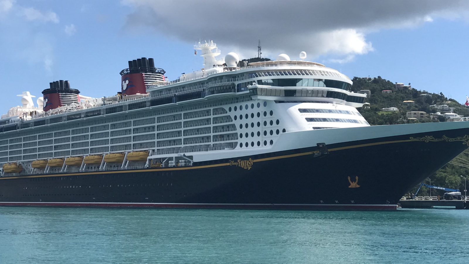The Disney Fantasy alongside at a Caribbean pier, in profile